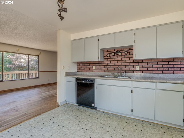 kitchen with gray cabinets, sink, black dishwasher, light hardwood / wood-style floors, and a textured ceiling