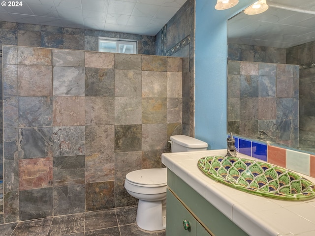 bathroom featuring vanity, tile walls, toilet, and tile patterned flooring