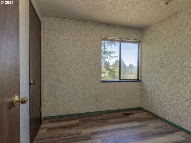 spare room featuring wood-type flooring and a textured ceiling