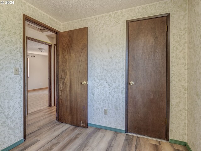 unfurnished bedroom with light hardwood / wood-style flooring and a textured ceiling