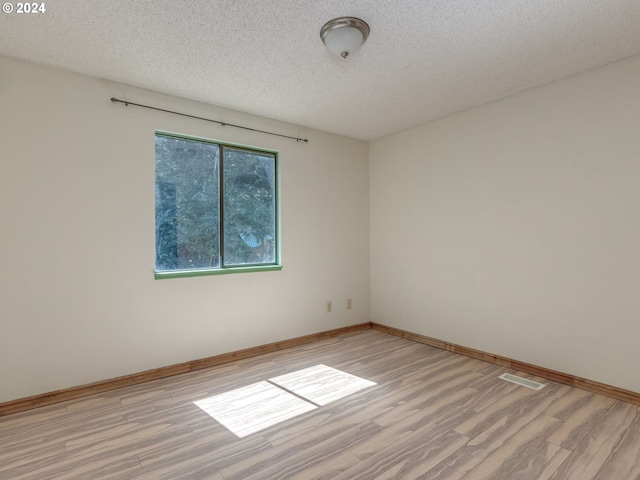 unfurnished room with a textured ceiling and wood-type flooring