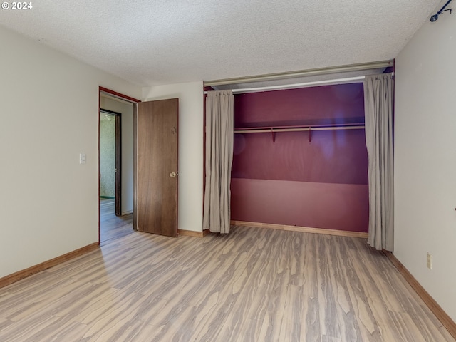 unfurnished bedroom with a closet, light wood-type flooring, and a textured ceiling