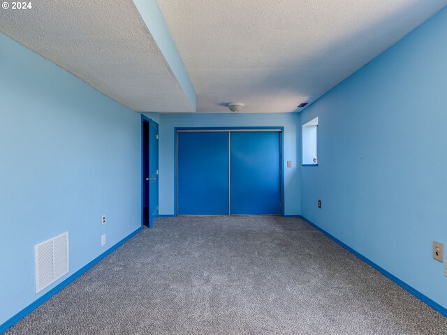 unfurnished bedroom with carpet, a closet, and a textured ceiling