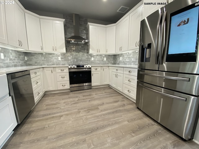 kitchen with white cabinetry, appliances with stainless steel finishes, wall chimney exhaust hood, and tasteful backsplash