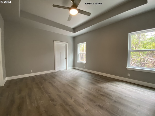 unfurnished bedroom featuring ceiling fan, dark hardwood / wood-style floors, and a raised ceiling