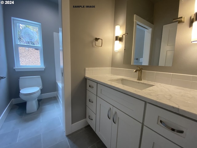 bathroom featuring toilet, vanity, a tub, and tile patterned floors