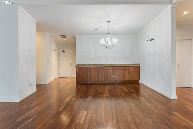 empty room with a notable chandelier, dark hardwood / wood-style floors, and ornamental molding