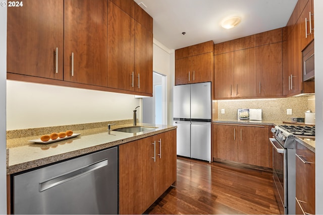 kitchen featuring light stone countertops, backsplash, stainless steel appliances, sink, and dark hardwood / wood-style floors