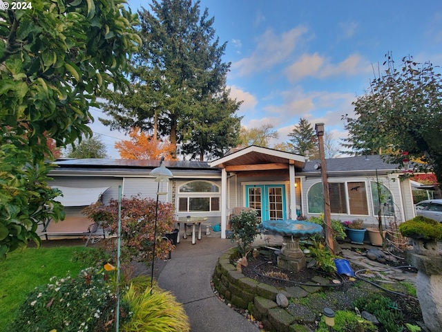 view of front facade with french doors, a patio, and solar panels