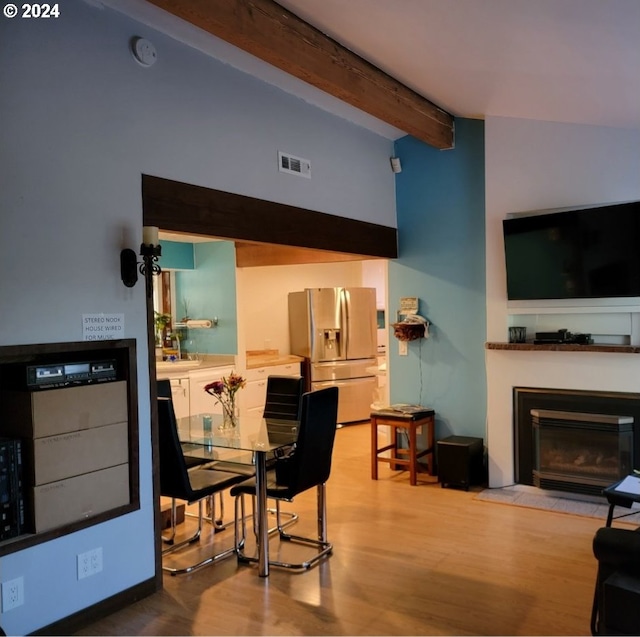 dining area featuring wood-type flooring and lofted ceiling with beams