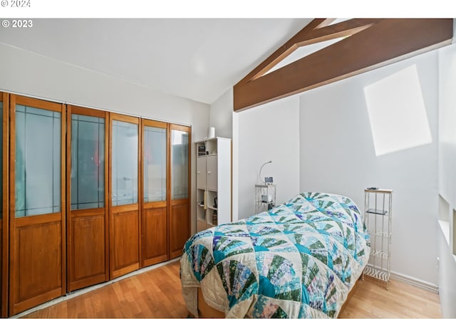 bedroom featuring a closet, lofted ceiling, and light hardwood / wood-style flooring