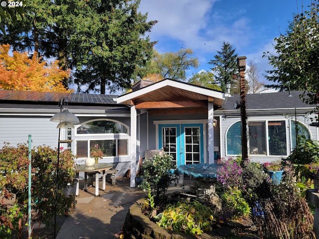 rear view of house with solar panels and french doors