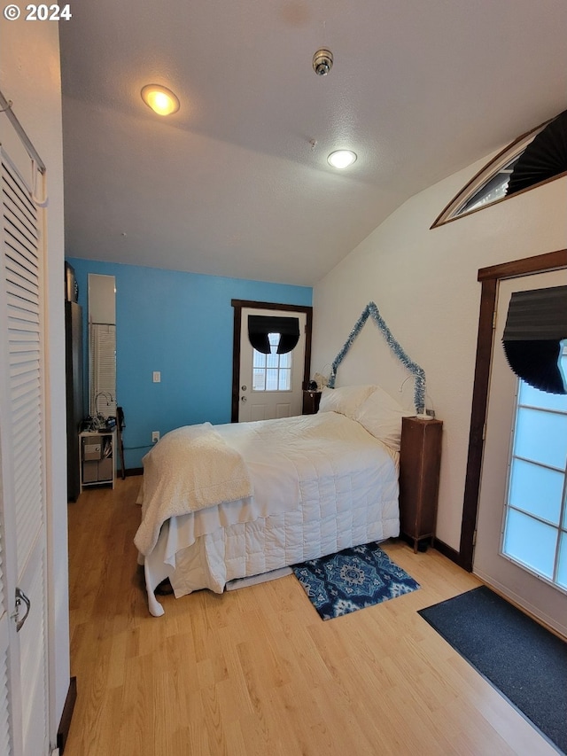 bedroom featuring multiple windows, light hardwood / wood-style flooring, and lofted ceiling