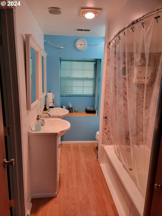 full bathroom featuring hardwood / wood-style floors, vanity, shower / bath combo, and toilet