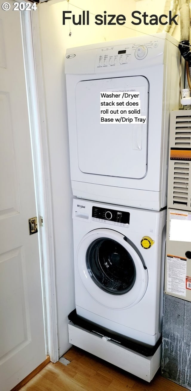 laundry area with hardwood / wood-style floors and stacked washer and clothes dryer