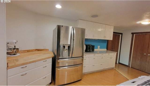 kitchen with white cabinetry, stainless steel fridge, light hardwood / wood-style floors, and wood counters