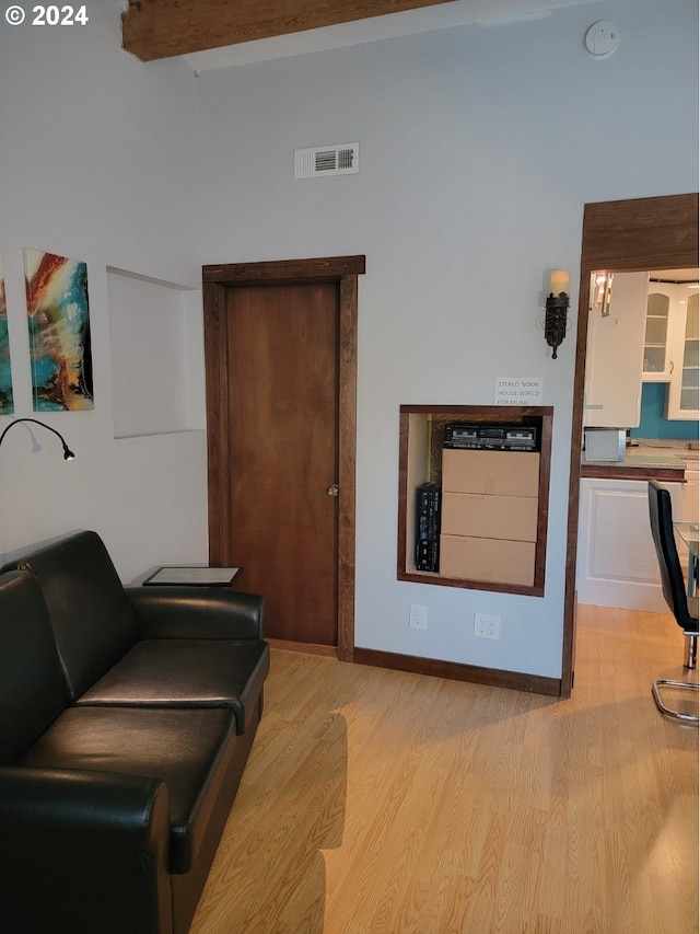 living room featuring beamed ceiling and light hardwood / wood-style floors