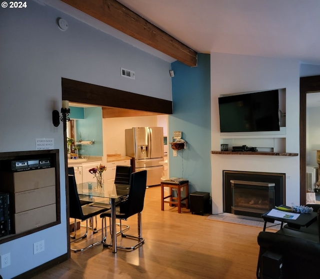 living room with hardwood / wood-style floors and vaulted ceiling with beams