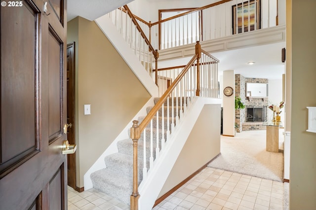 stairs featuring carpet and a brick fireplace