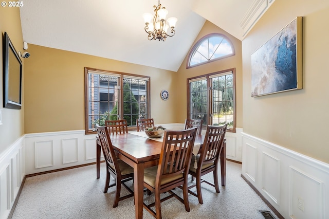 dining space featuring a notable chandelier, light colored carpet, and vaulted ceiling