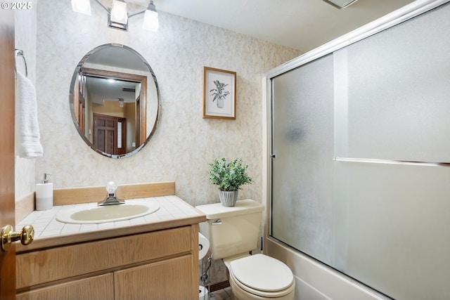 full bathroom with combined bath / shower with glass door, vanity, and toilet