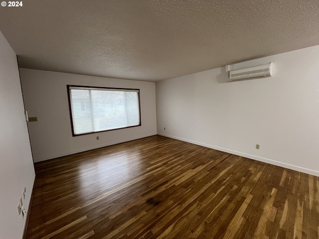 empty room featuring a wall mounted air conditioner, dark wood-type flooring, and a textured ceiling