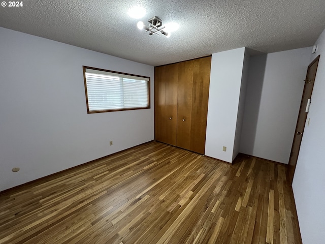 unfurnished bedroom with wood-type flooring, a textured ceiling, and a closet