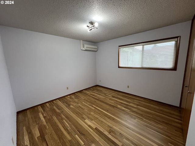 spare room with hardwood / wood-style floors, a textured ceiling, and a wall unit AC