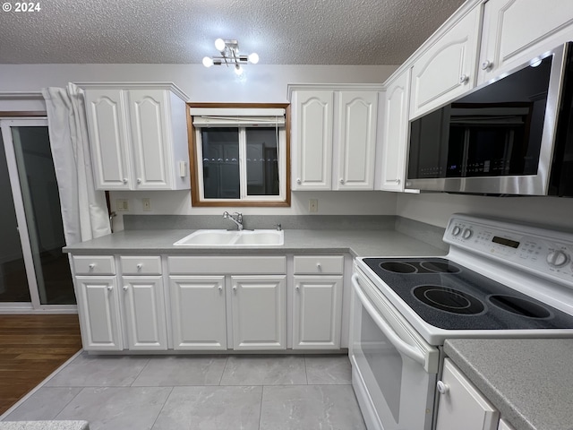 kitchen featuring sink, white electric stove, a textured ceiling, light tile patterned flooring, and white cabinetry