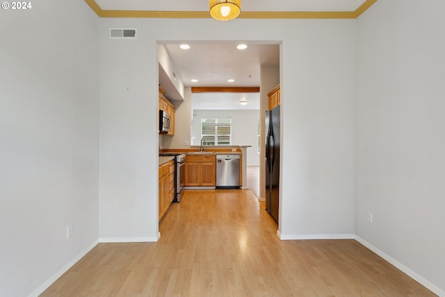 kitchen with appliances with stainless steel finishes, light hardwood / wood-style flooring, ornamental molding, and sink