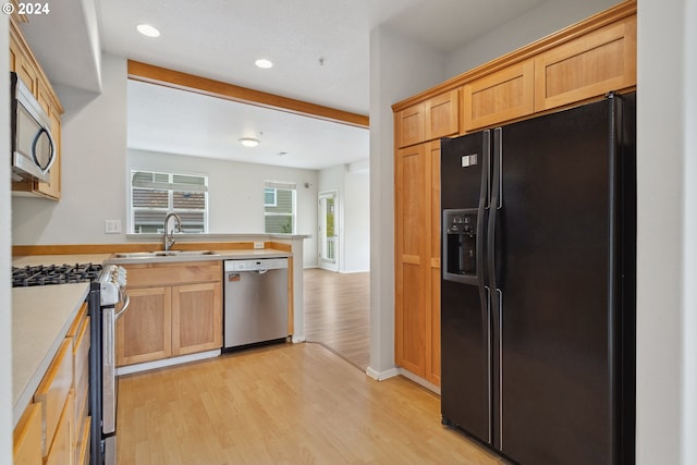 kitchen featuring sink, beamed ceiling, light hardwood / wood-style flooring, and appliances with stainless steel finishes