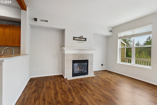 unfurnished living room featuring dark hardwood / wood-style flooring, sink, and a tile fireplace