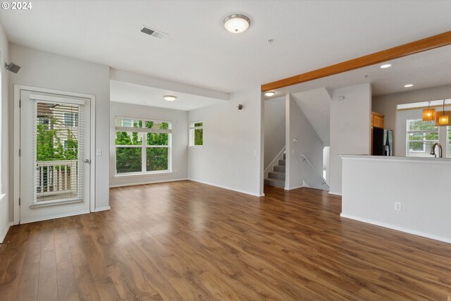 unfurnished living room featuring sink, beamed ceiling, and dark wood-type flooring