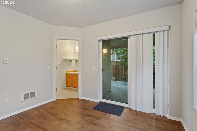 unfurnished room featuring a textured ceiling and light hardwood / wood-style flooring