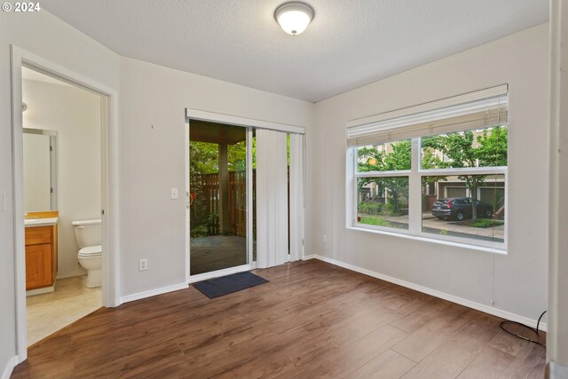 spare room with a textured ceiling, dark hardwood / wood-style flooring, and plenty of natural light