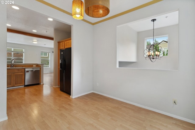 kitchen featuring stainless steel dishwasher, black refrigerator with ice dispenser, sink, pendant lighting, and light hardwood / wood-style flooring