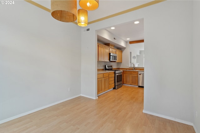 kitchen featuring sink, light hardwood / wood-style flooring, crown molding, pendant lighting, and appliances with stainless steel finishes