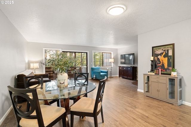 dining area with a textured ceiling and light wood-type flooring