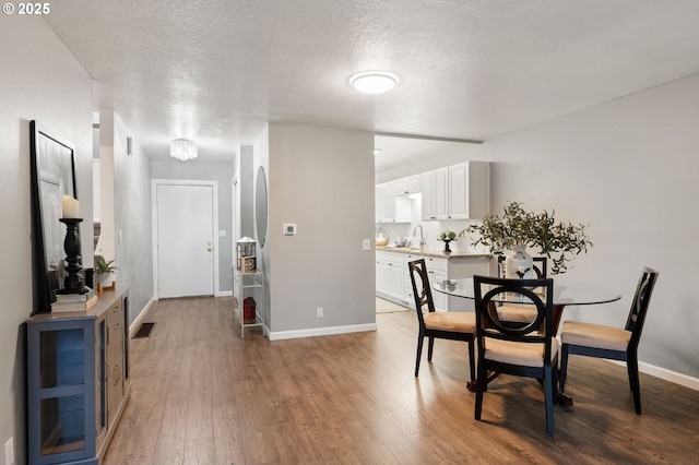 dining area with sink, a textured ceiling, and hardwood / wood-style flooring