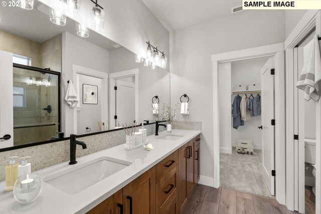 bathroom featuring hardwood / wood-style flooring, vanity, toilet, and a shower with shower door