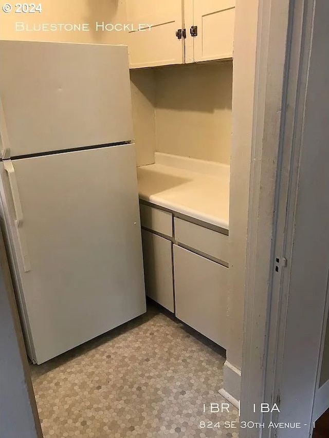 kitchen featuring fridge and white cabinets