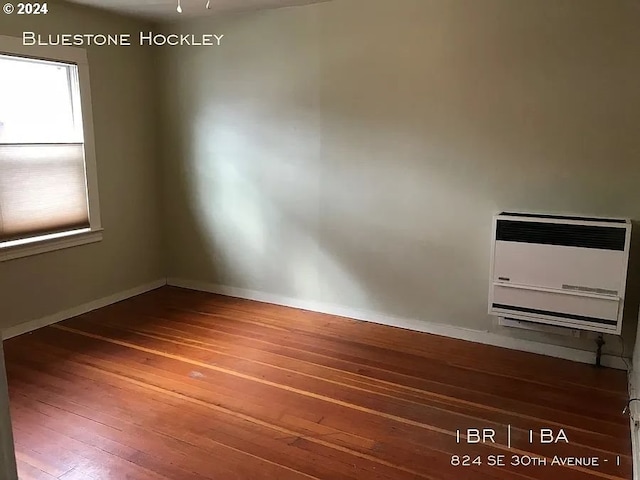 unfurnished room with hardwood / wood-style floors and heating unit