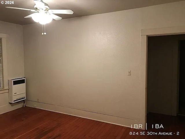 spare room with heating unit, ceiling fan, and dark hardwood / wood-style flooring