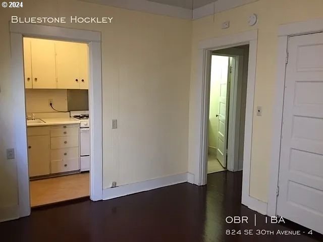 unfurnished bedroom featuring ensuite bath, sink, and dark hardwood / wood-style flooring