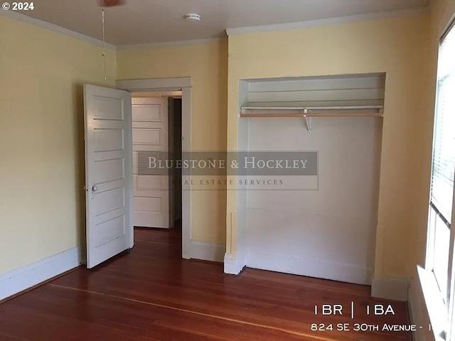 unfurnished bedroom with a closet, dark wood-type flooring, and crown molding