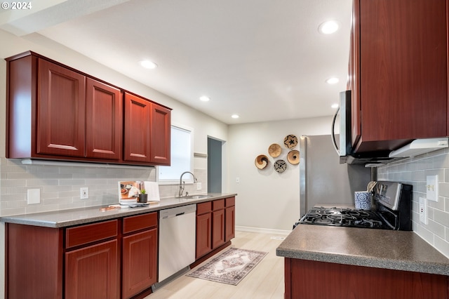 kitchen with light wood-type flooring, appliances with stainless steel finishes, sink, and decorative backsplash