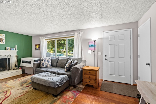 living room with a textured ceiling, a brick fireplace, and hardwood / wood-style flooring