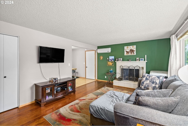 living room with wood-type flooring, a textured ceiling, a fireplace, and a wall mounted air conditioner