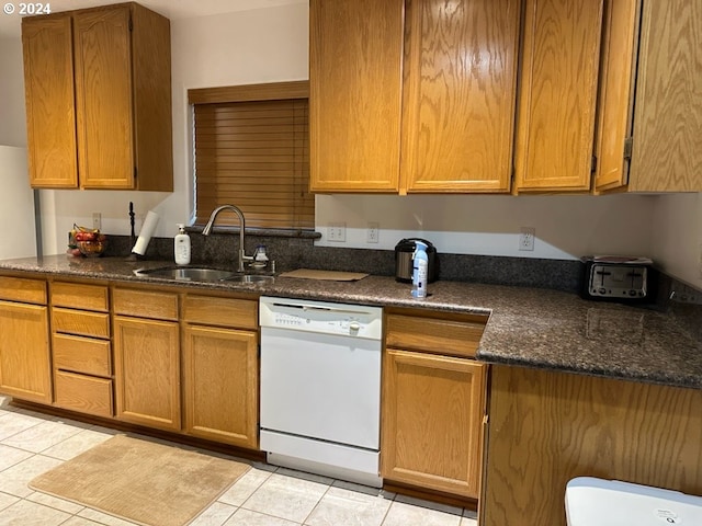 kitchen with dishwasher, dark stone countertops, light tile patterned floors, and sink