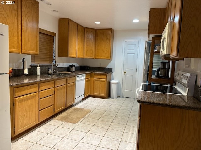 kitchen featuring sink, light tile patterned floors, dark stone counters, and white appliances